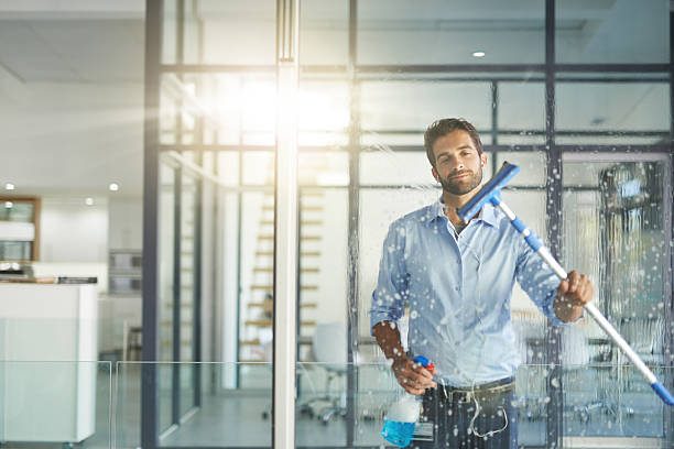 Cropped shot of a young man cleaning windows in an office